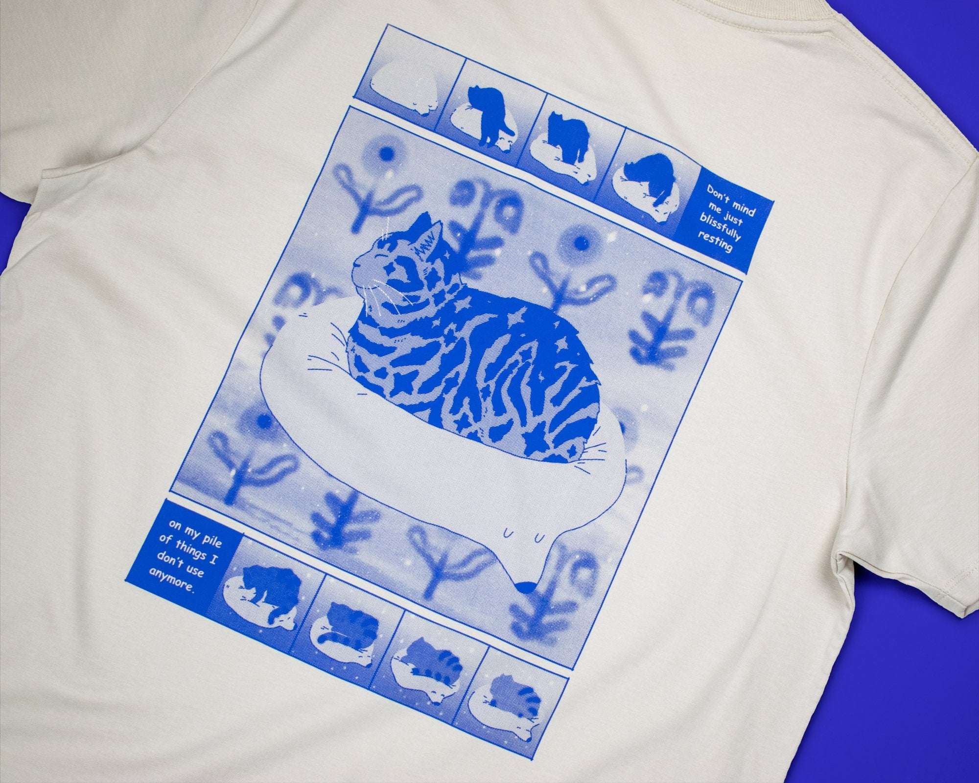Bliss t-shirt | Hand screen printed on sand/beige organic cotton tee with blue comic style illustration of a tabby cat getting comfy