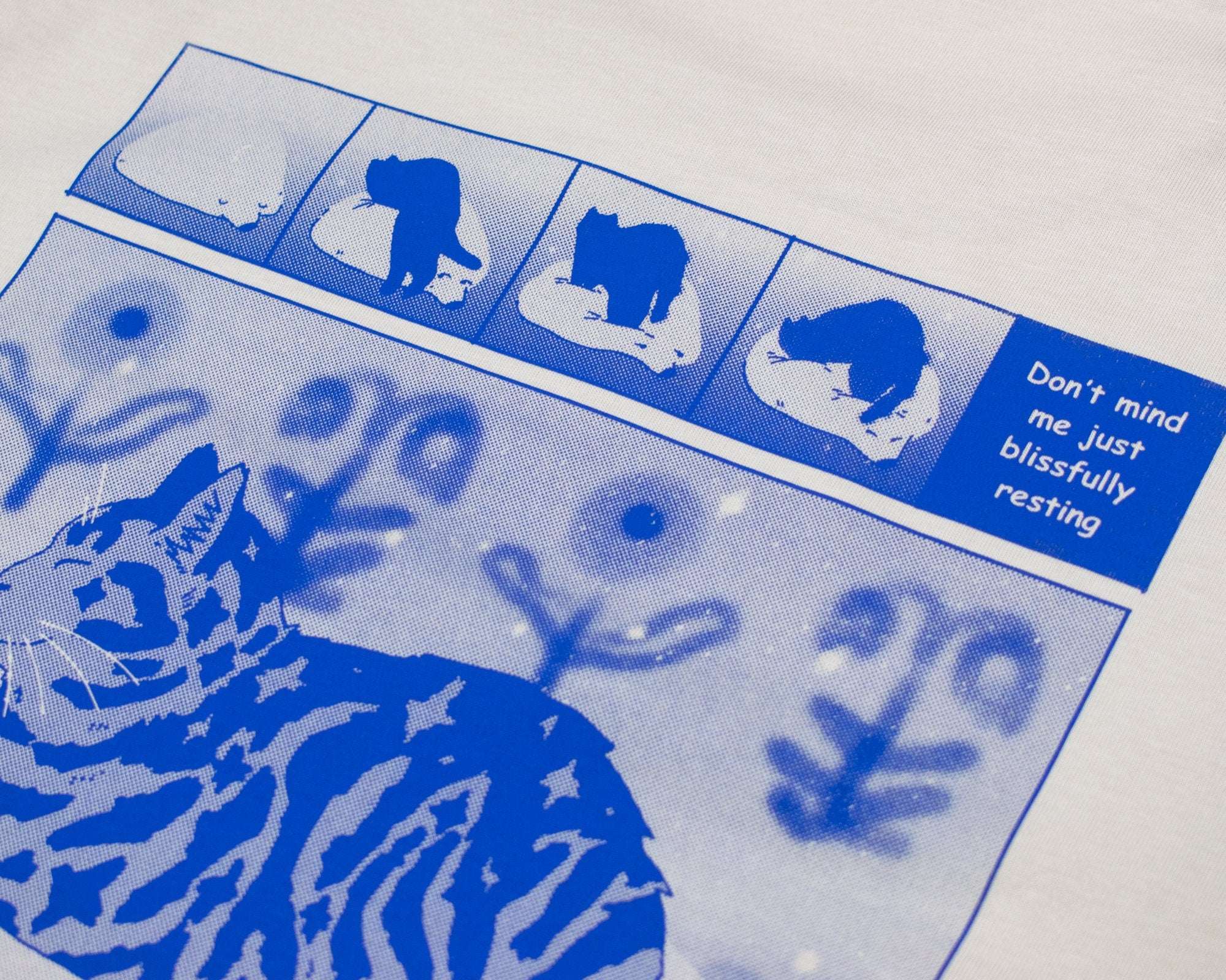 Bliss t-shirt | Hand screen printed on sand/beige organic cotton tee with blue comic style illustration of a tabby cat getting comfy