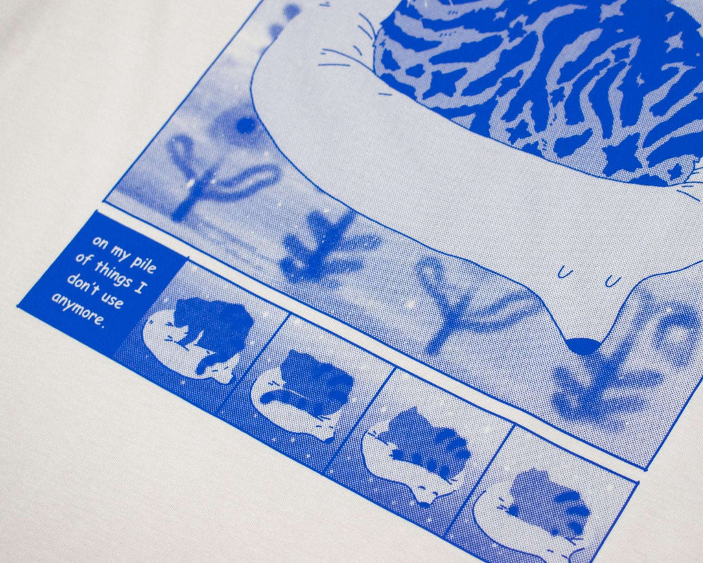 Bliss t-shirt | Hand screen printed on sand/beige organic cotton tee with blue comic style illustration of a tabby cat getting comfy