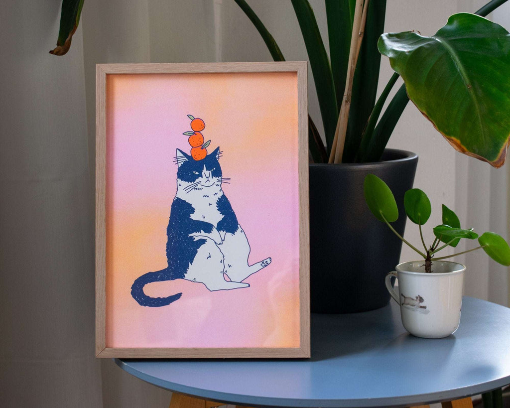 Orange Cat A4 Risograph poster | Illustration in fluorescent pink, yellow and federal blue of a grumpy cat that balances oranges on its head