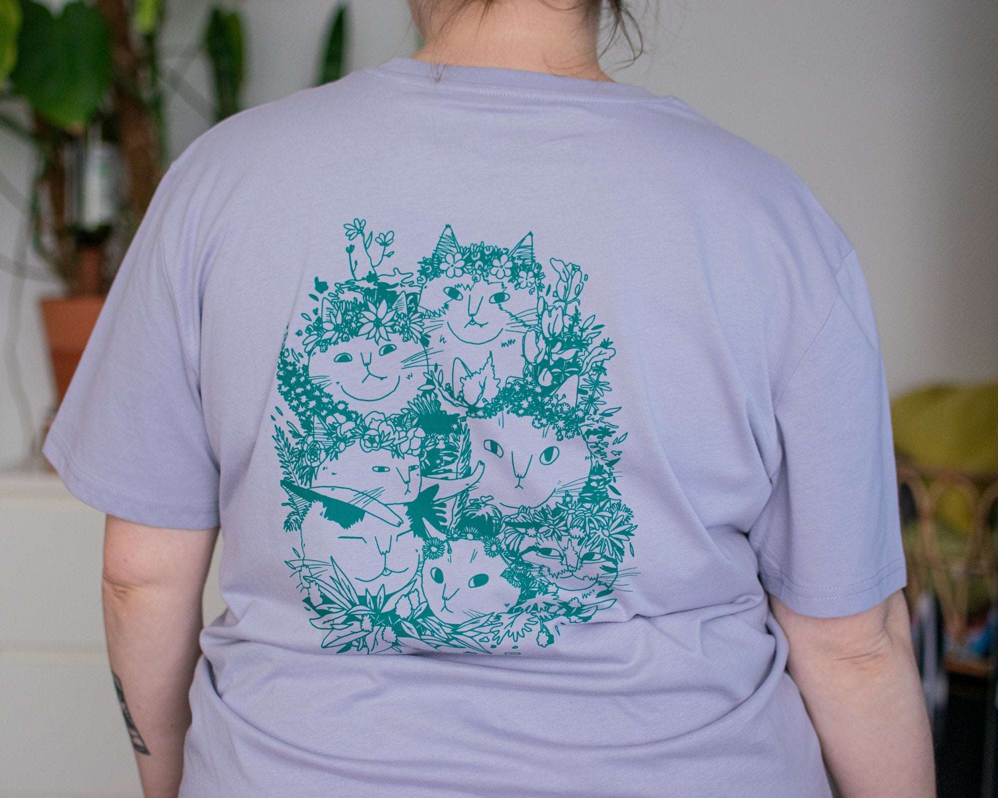 Summer Bouquet T-Shirt | Hand screen printed illustration of 7 cats with flowercrowns and other plants in green on lilac organic cotton tee