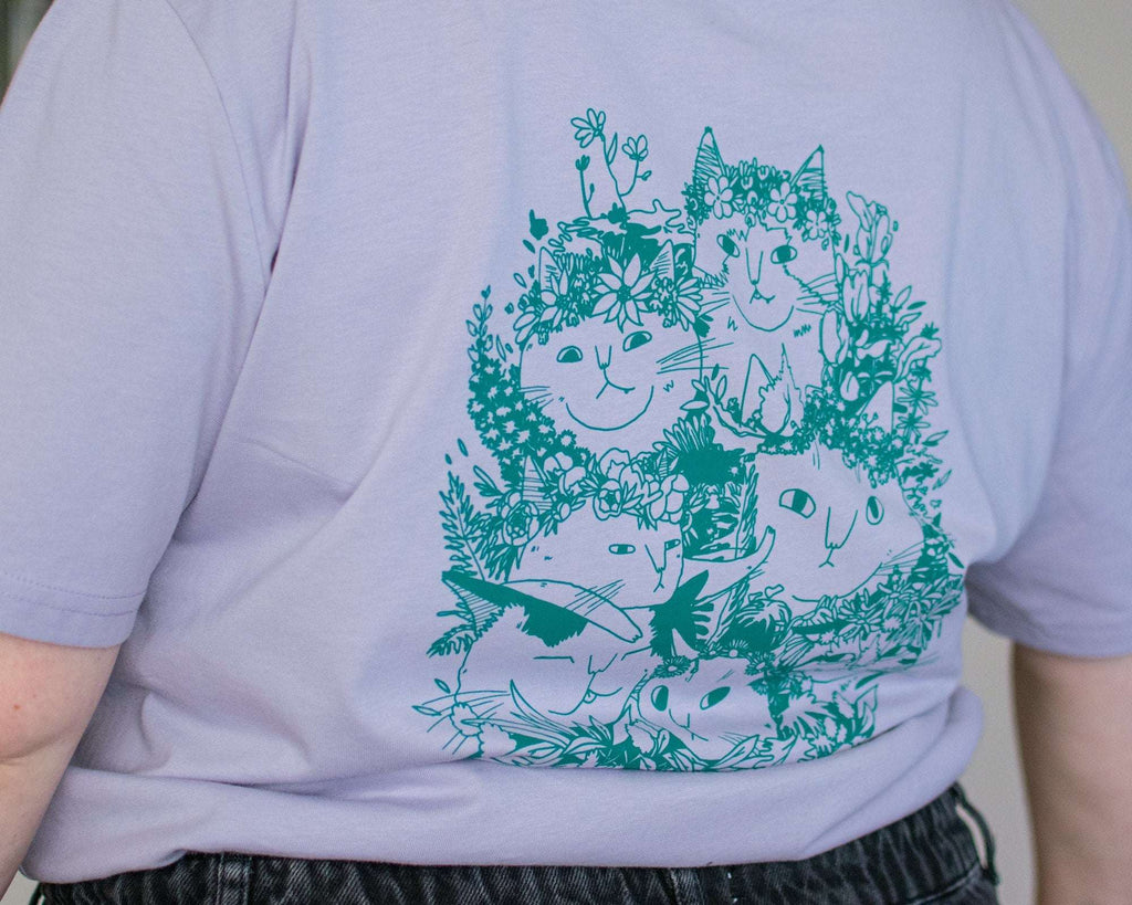 Summer Bouquet T-Shirt | Hand screen printed illustration of 7 cats with flowercrowns and other plants in green on lilac organic cotton tee