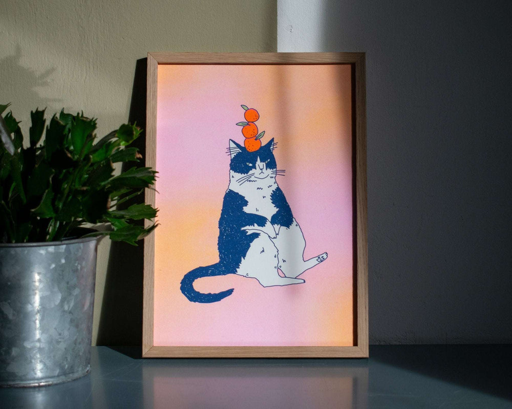 Orange Cat A4 Risograph poster | Illustration in fluorescent pink, yellow and federal blue of a grumpy cat that balances oranges on its head