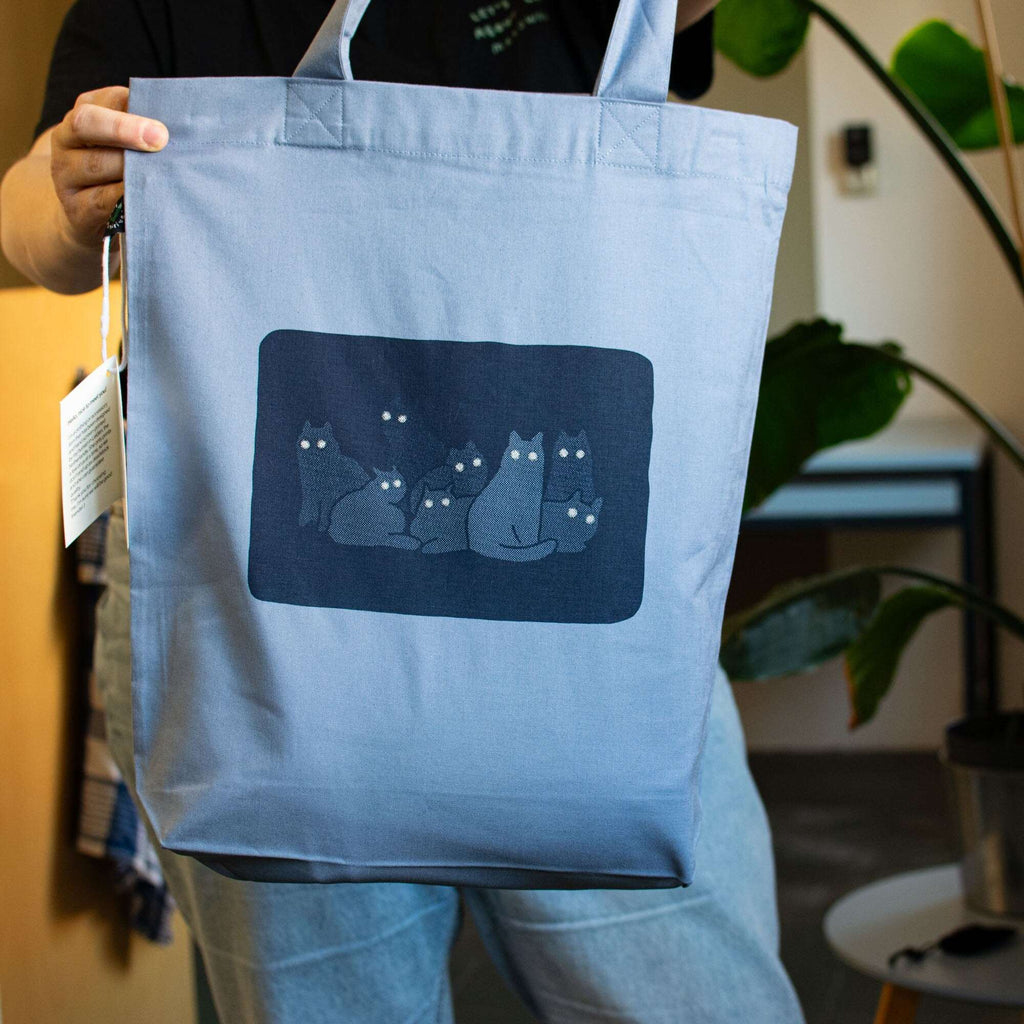 Reflecting cat eyes | Tote Bag with hand screen printed illustration of a bunch of cat silhouettes in the dark who's eyes are glowing