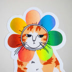 Grumpy Flower Cat | Holographic vinyl sticker of a irritable orange tabby cat wearing a rainbow colored flower petal costume around its head