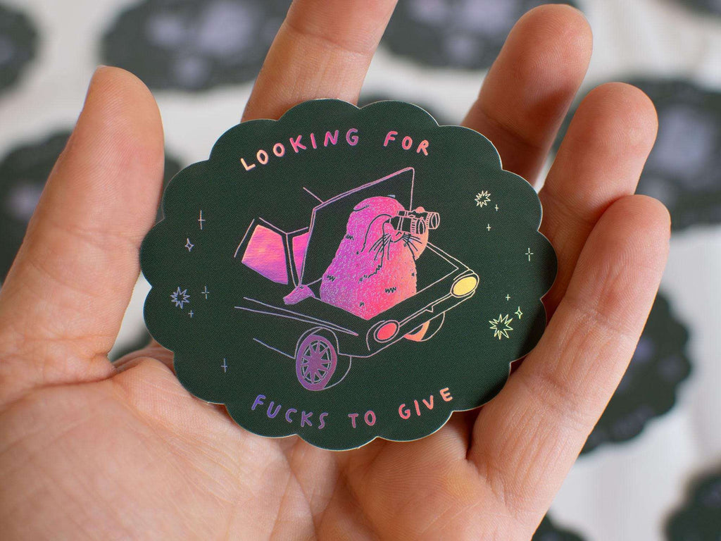 Looking for fucks to give 2.0 | Holographic Cat Sticker of a cat sitting in the trunk of a car looking for f***s to give through binoculars