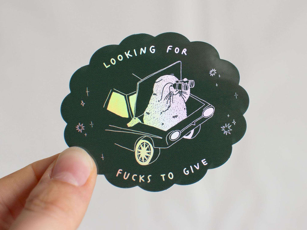 Looking for fucks to give 2.0 | Holographic Cat Sticker of a cat sitting in the trunk of a car looking for f***s to give through binoculars