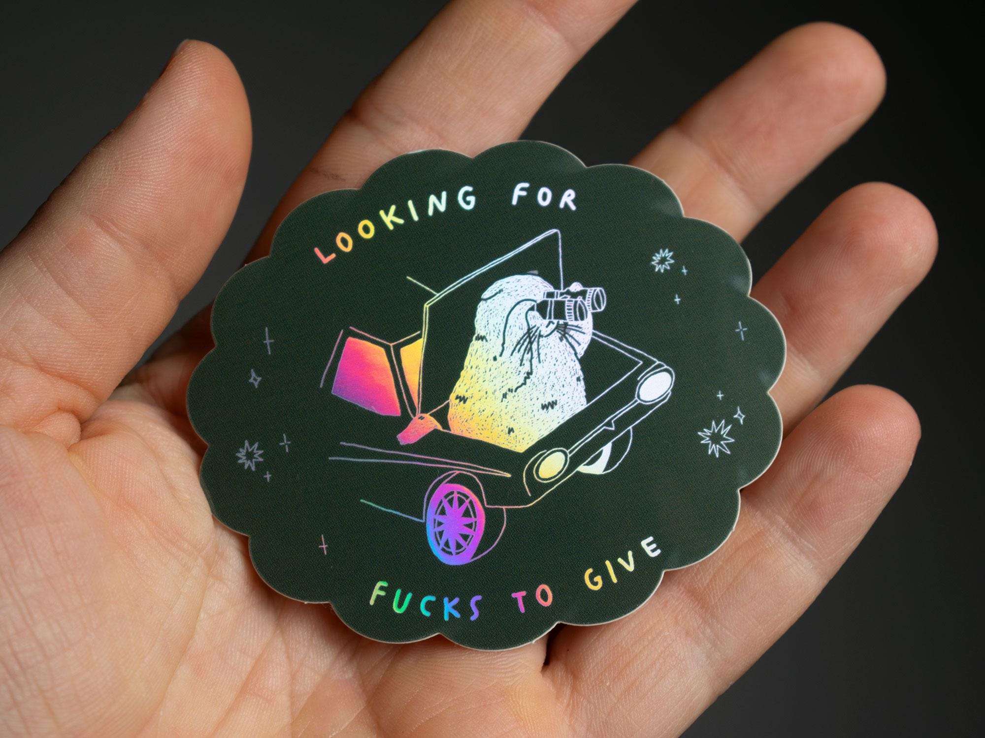 Looking for fucks to give 2.0 | Holographic Cat Sticker of a cat sitting in the trunk of a car looking for f***s to give through binoculars