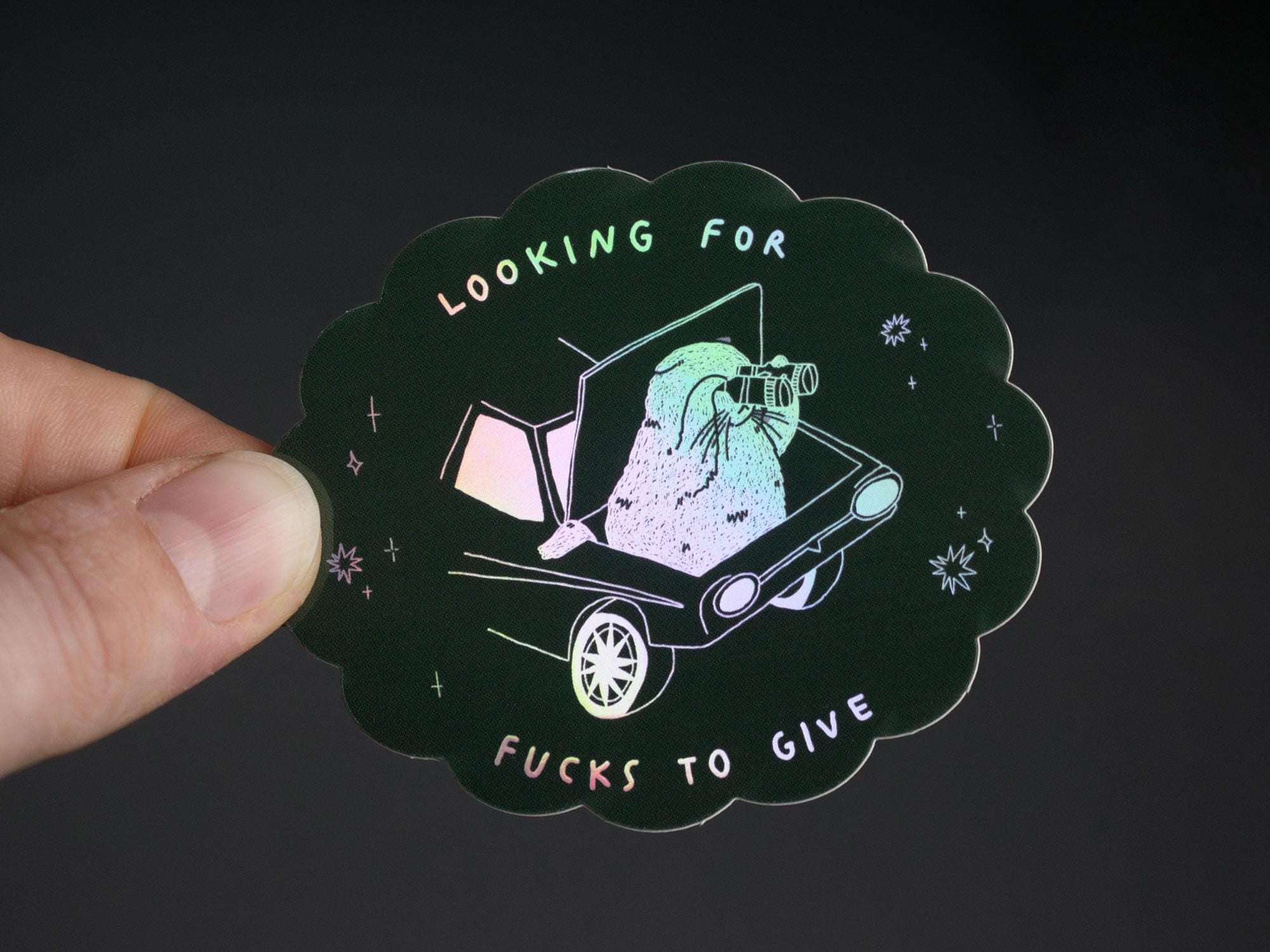 Looking for fucks to give 2.0 | Holographic Cat Sticker of a cat sitting in the trunk of a car looking for f***s to give through binoculars
