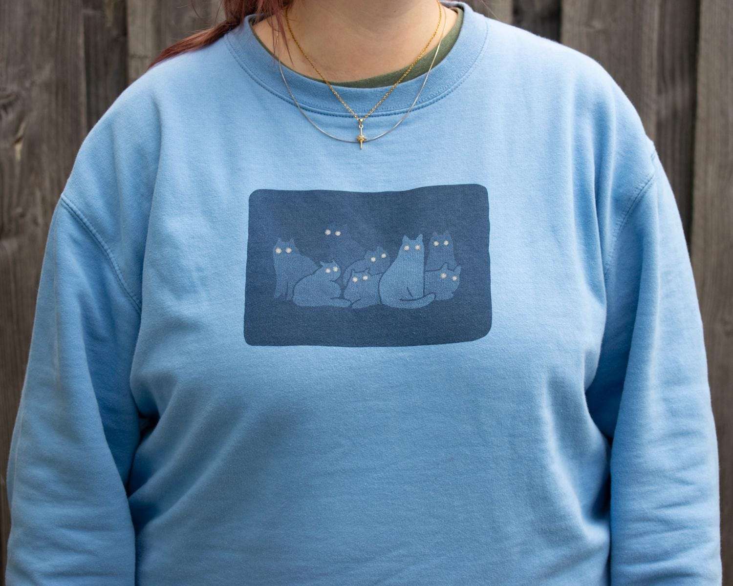 Reflecting eyes sweatshirt with a hand screen printed illustration of a bunch of cats in the dark