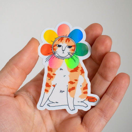 Grumpy Flower Cat | Holographic vinyl sticker of a irritable orange tabby cat wearing a rainbow colored flower petal costume around its head