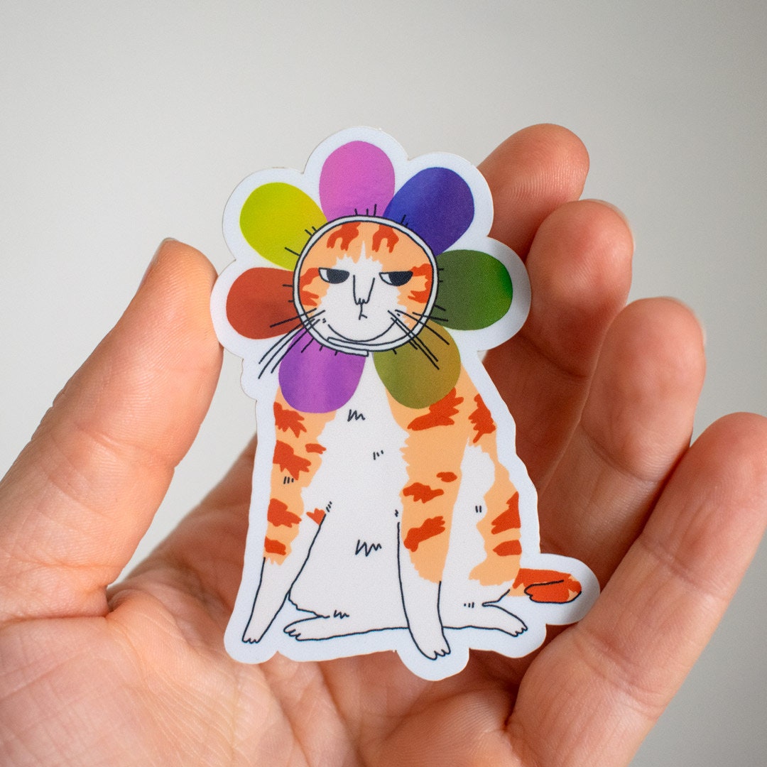 Grumpy Flower Cat | Holographic vinyl sticker of a irritable orange tabby cat wearing a rainbow colored flower petal costume around its head