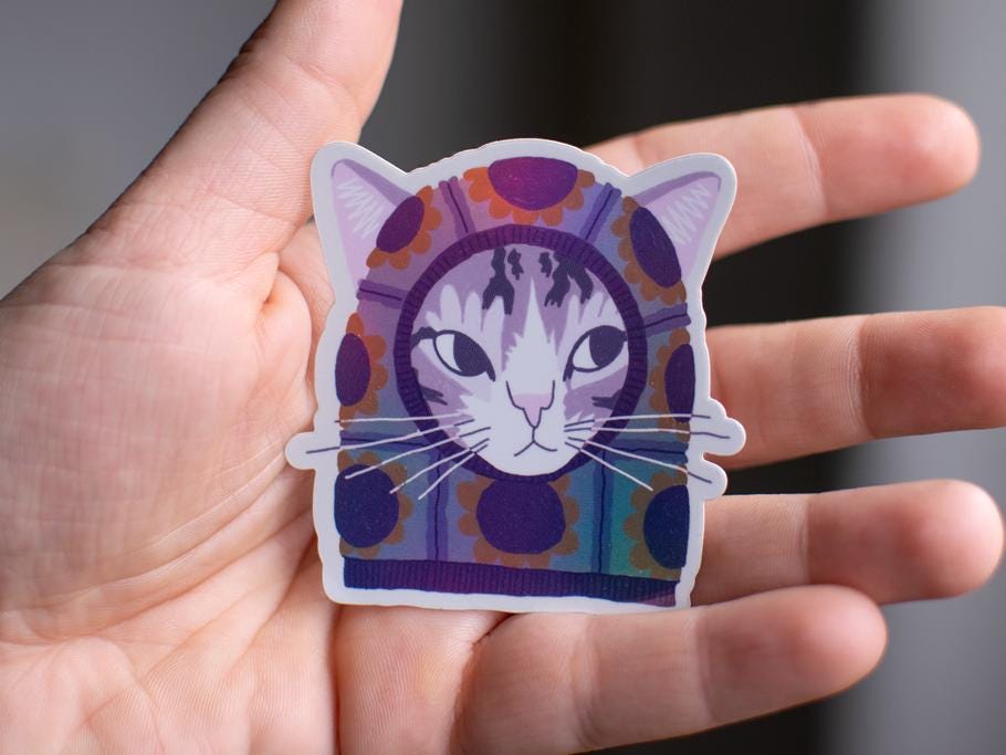 Sunflower Balaclava Cat | Cute holographic vinyl sticker of a purple tabby cat wearing a balaclava with flowers on it