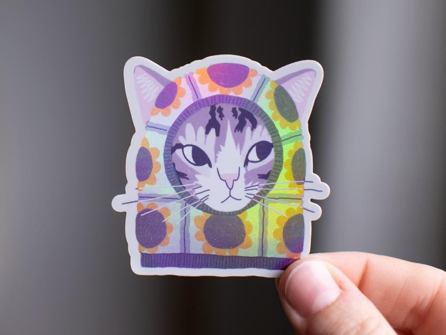 Sunflower Balaclava Cat | Cute holographic vinyl sticker of a purple tabby cat wearing a balaclava with flowers on it