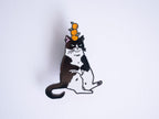 Orange Balance Cat Enamel Pin | Black nickel plated brooch with a tuxedo cat balancing three oranges on its head