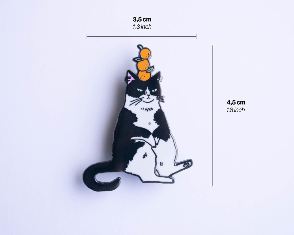 Orange Balance Cat Enamel Pin | Black nickel plated brooch with a tuxedo cat balancing three oranges on its head