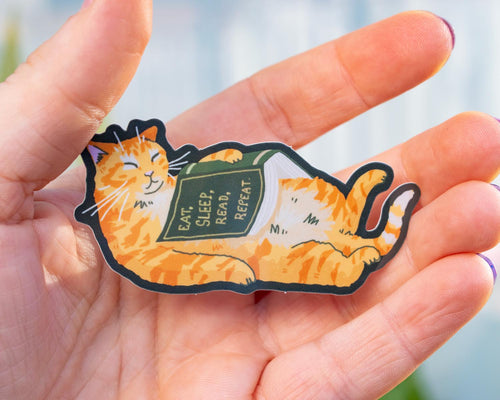 Eat, sleep, read, repeat | Holographic cat Sticker for bookish people with a sleepy orange cat and a green book in its belly