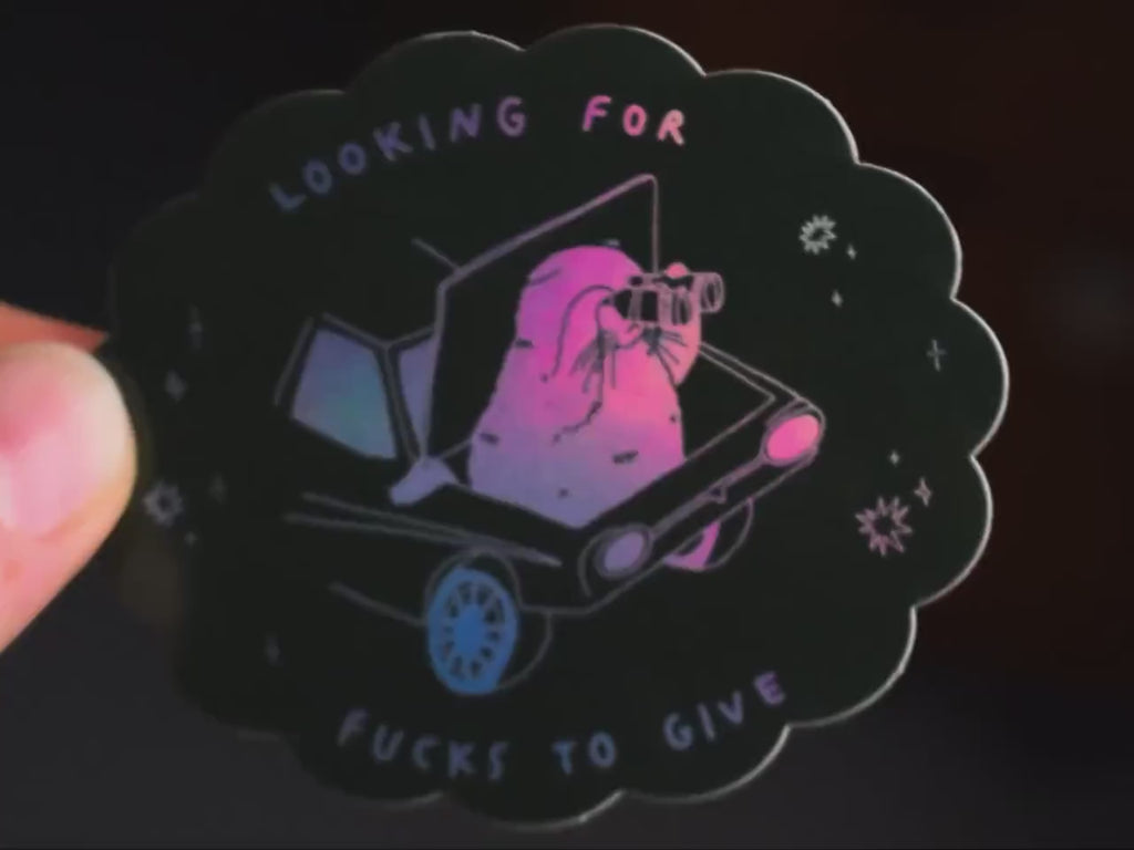 Looking for fucks to give 2.0 | Holographic Cat Sticker of a cat sitting in the trunk of a car looking for f***s to give through binoculars